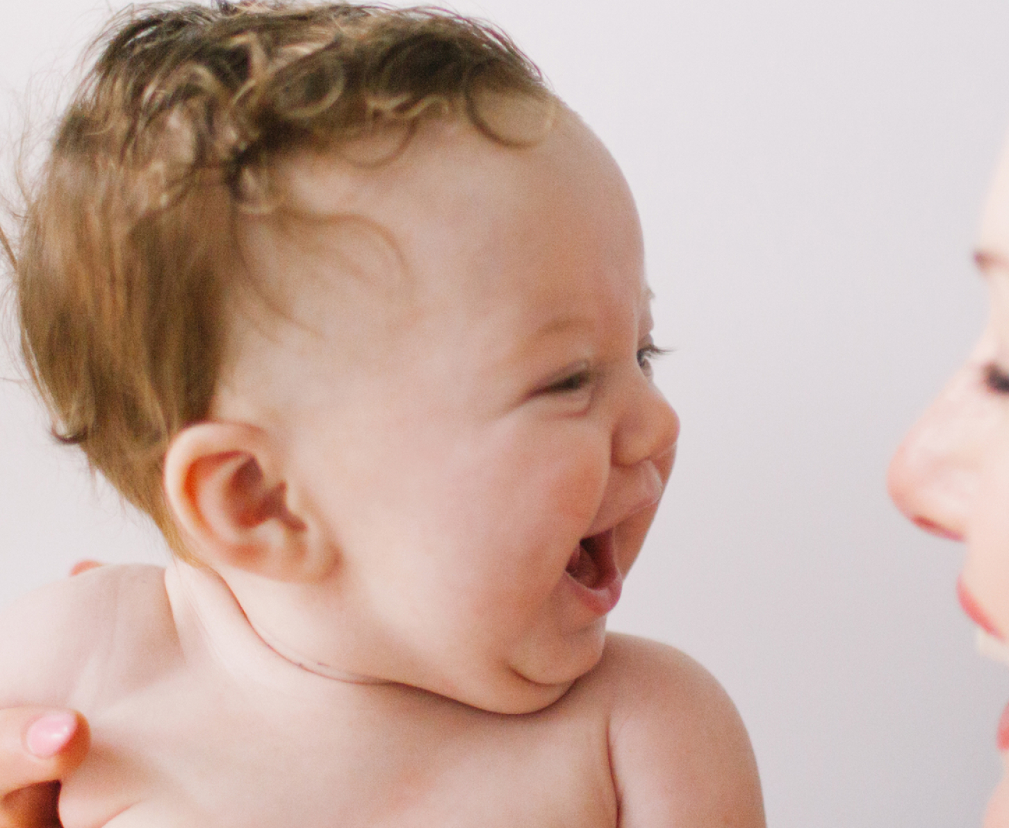 A mother laughing with her baby who is giggling happily